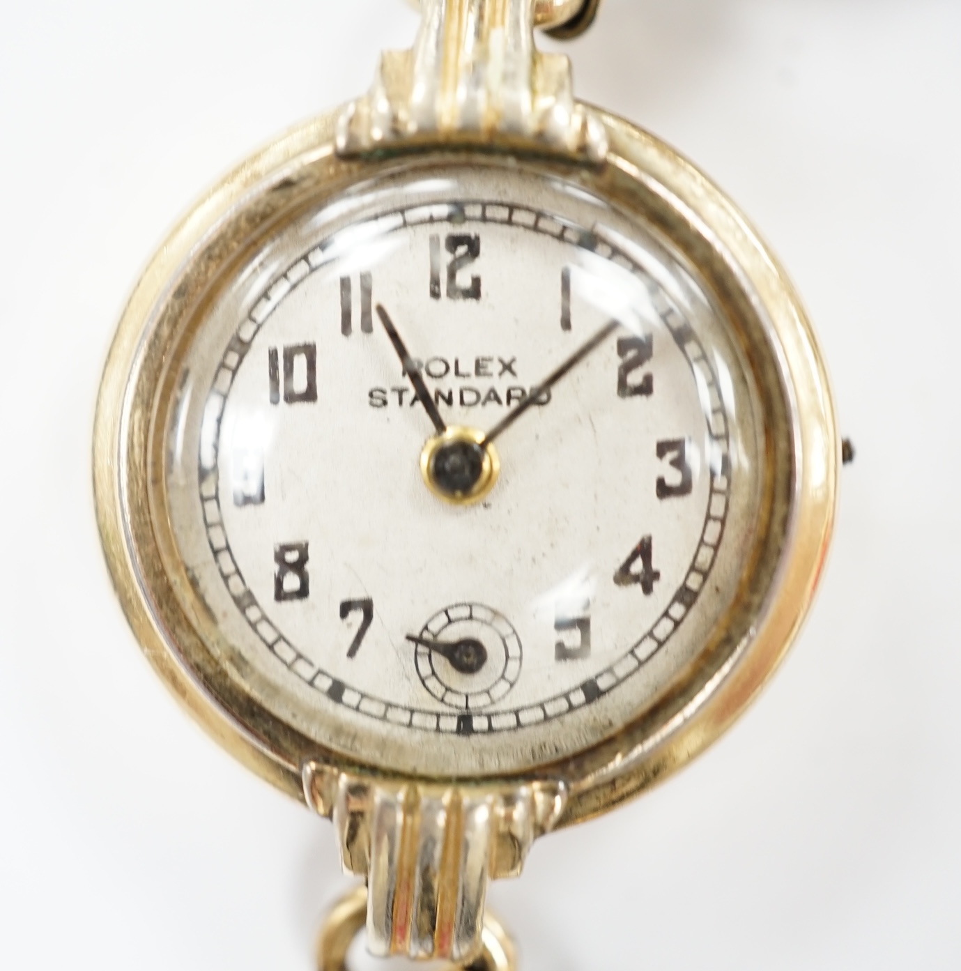 A lady's gilt metal manual wind wrist watch, the dial inscribed 'Rolex Standard', movement unsigned and no winding crown, on an associated flexible link bracelet. Condition - poor